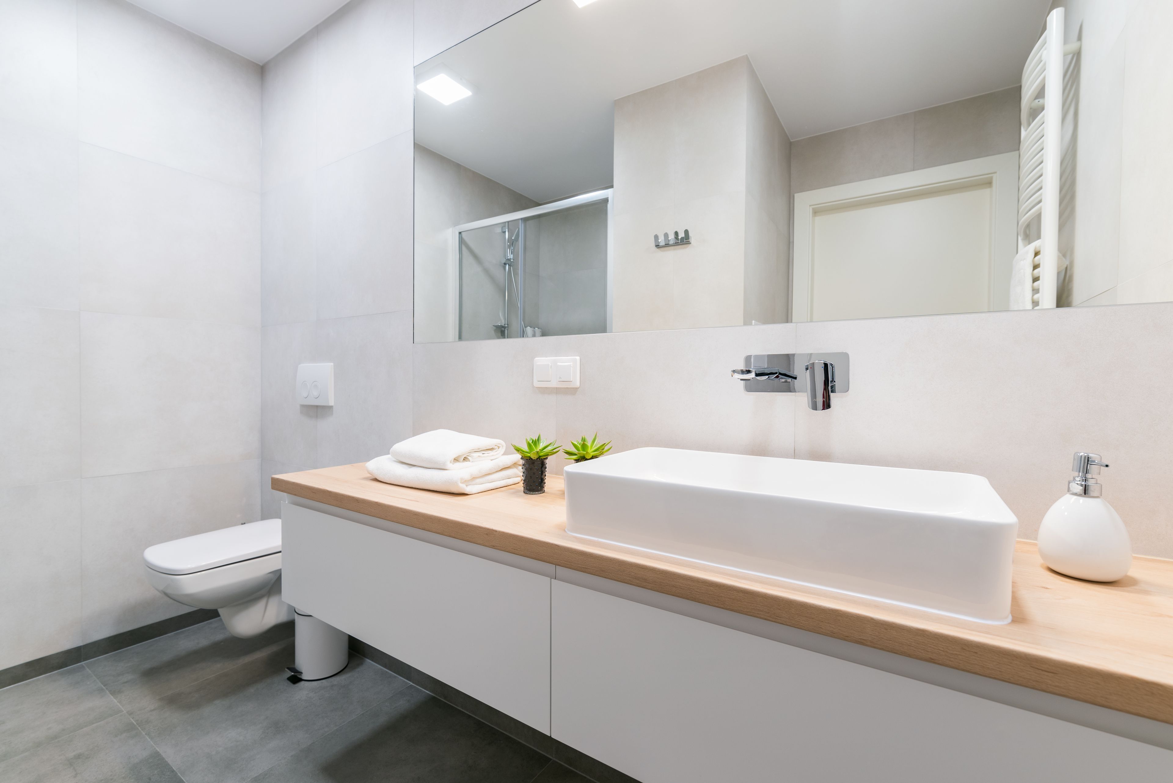 Een moderne badkamer met een wit wastafel, een spiegel en een toilet.