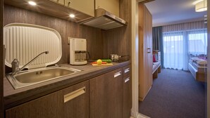 Pieni hotellihuone, jossa on minikeittiö, sänky ja kylpyhuone.