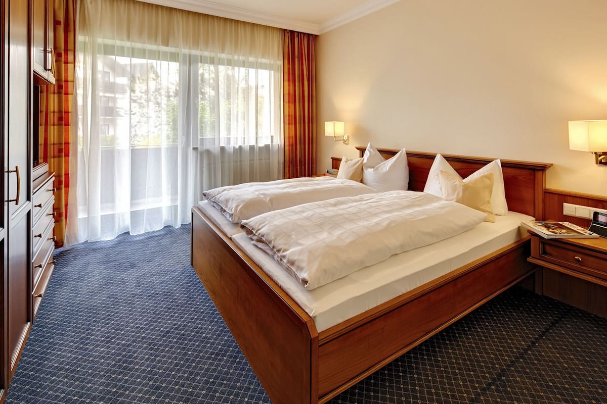 A hotel room with a large bed, two bedside tables, a desk, and a wardrobe.