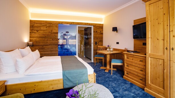 Hotellihuone, jossa on puinen sänky, työpöytä tuolilla, televisio ja vaatekaappi.