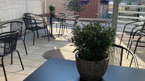 Un espace extérieur aménagé avec des tables et des chaises, un pot de fleurs et un plateau contenant de la nourriture et des boissons.