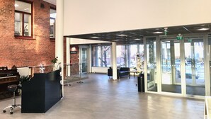 Un hall d’entrée spacieux avec un plafond haut, un comptoir d’accueil, un piano et de grandes fenêtres donnant sur l’extérieur.