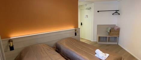 A hotel room with two beds, a small seating area, and a door leading to a bathroom.