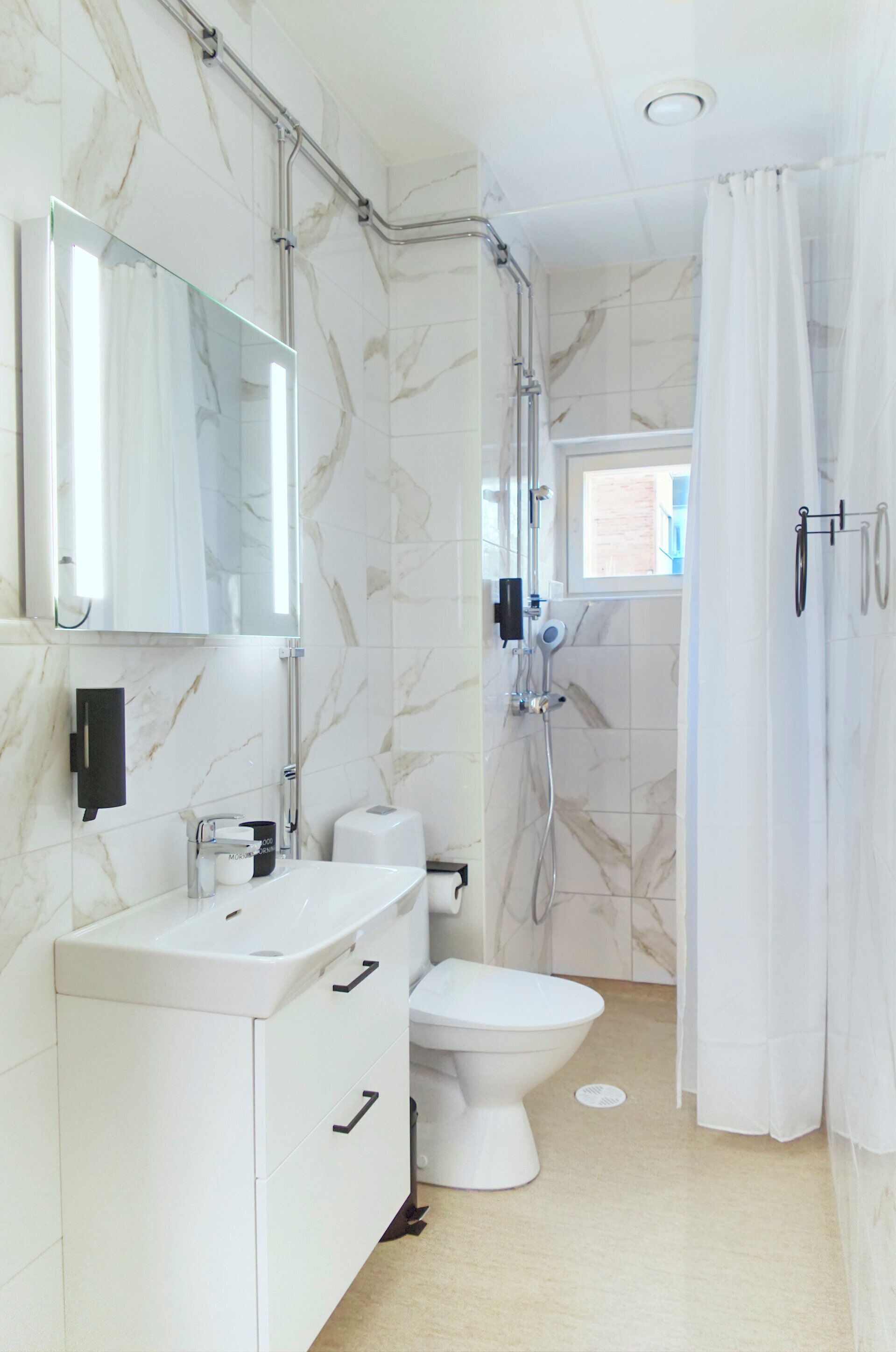 A bathroom with a white vanity, a toilet, a shower, and a mirror.