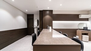Una sala riunioni moderna con un lungo tavolo, sedie, una scrivania con un computer e un condizionatore d'aria.