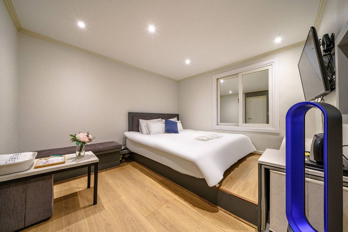 A modern hotel room with a bed, a desk with a computer, and a large mirror.