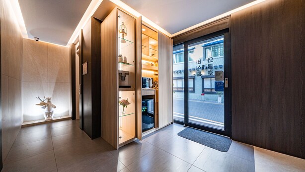 Una hall d'albergo moderna con una reception in legno, un'uscita in vetro e una piccola pianta da interno.