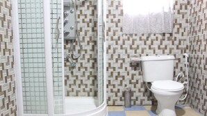 A bathroom with a shower, toilet, and patterned tile walls.