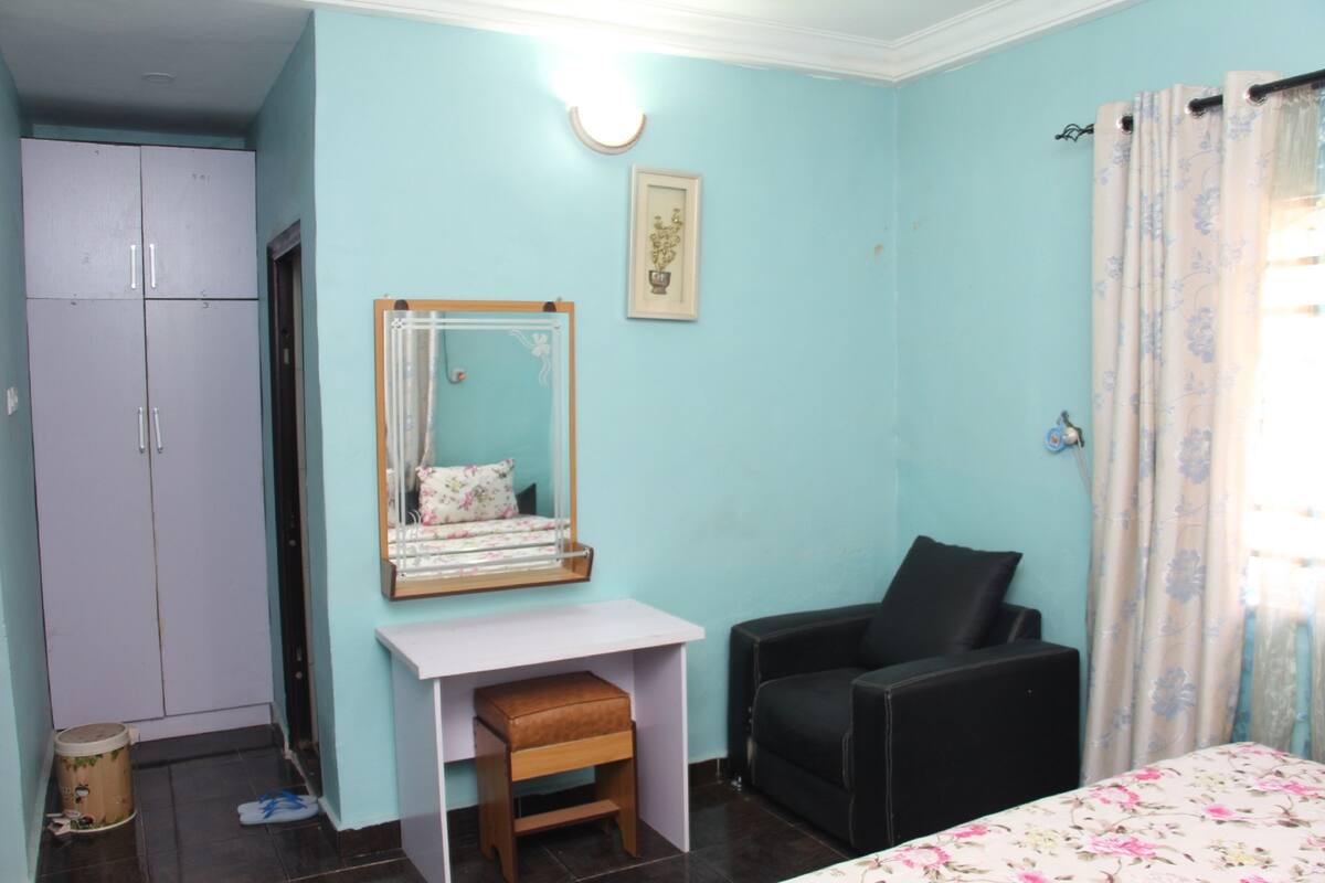 A room with a bed, a desk, a chair, a wardrobe, and a mirror.