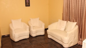 A room with two white armchairs and a white sofa against a yellow wall.