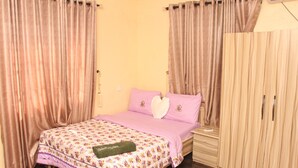 A bedroom with a bed, curtains, a wardrobe, and a nightstand.