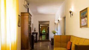 A hallway with a wooden cabinet, a yellow sofa, and a painting on the wall. - Domus Sicily - Fattoria Gorgo - Contessa Entellina (Abbazia di Santa Maria del Bosco)