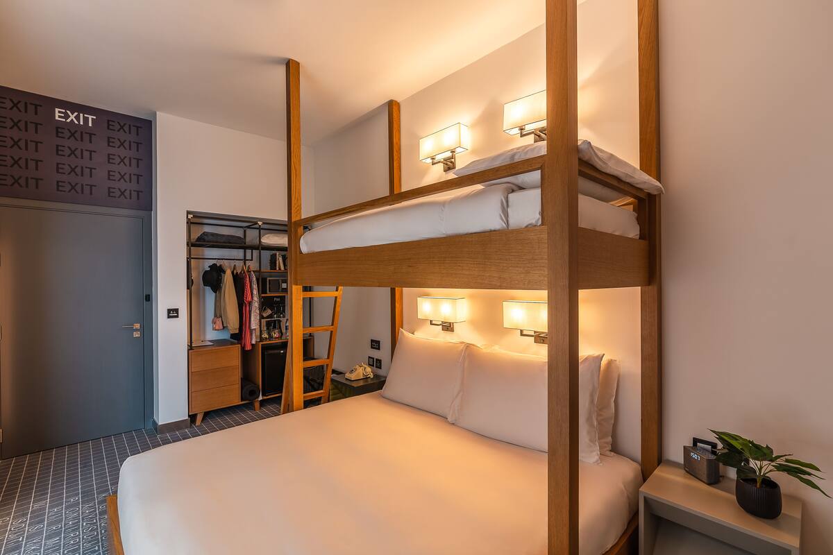 Ein Etagenbett mit Nachttisch, ein Beistelltisch mit Lampe und ein Schrank mit Spiegel.