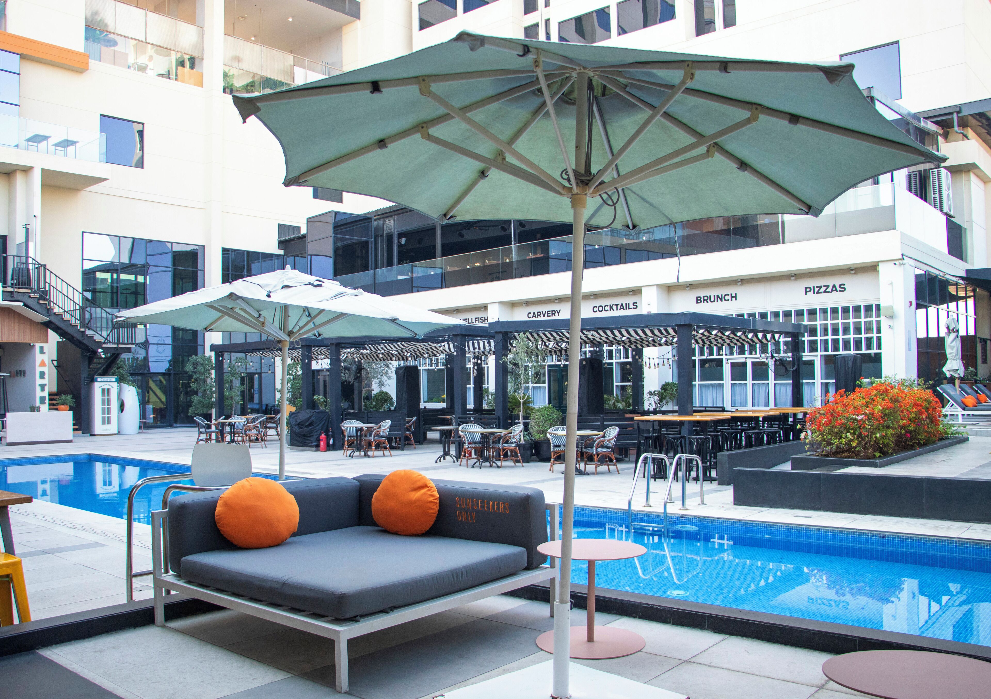 A poolside area with a sofa, umbrellas, and outdoor seating.
