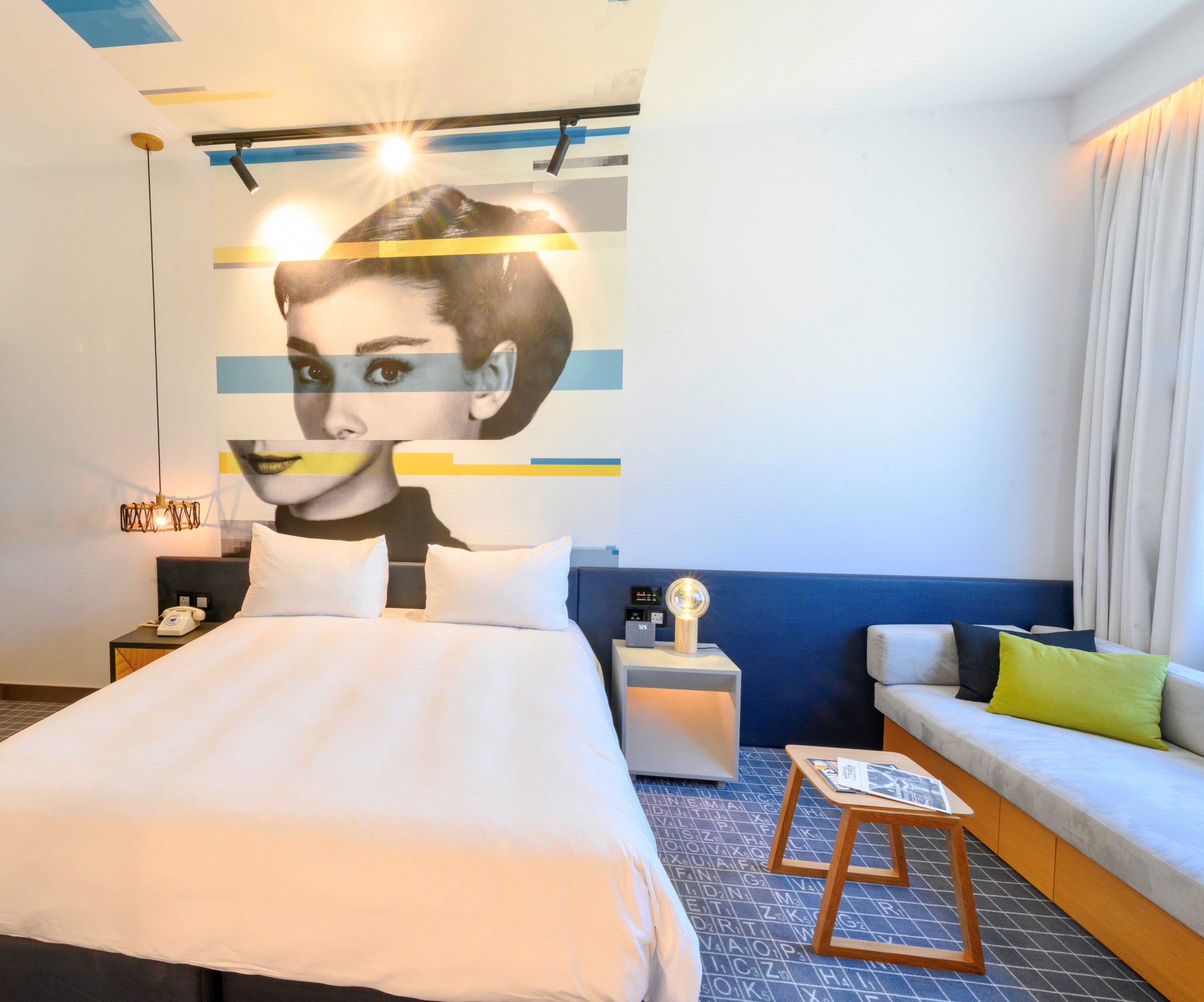 Ein modernes Hotelzimmer mit einem großen Bett, einer Couch, einem kleinen Tisch und einem an der Wand befestigten Kunstwerk.