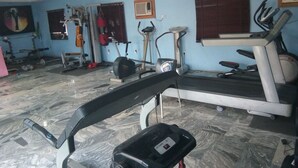 A gym with a treadmill, elliptical, and weight machines.