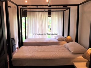 Two single beds with white mattresses and matching pillows, set against a modern backdrop with black trim.