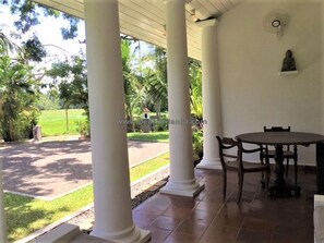 Relax in this serene outdoor space, surrounded by lush greenery and elegant columns.