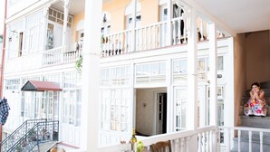 A multi-story building with balconies, a dining area with a table and chairs, and a staircase. - Meidan Suites (Tbilisi)