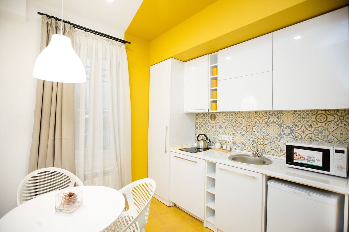 A compact kitchen with white cabinets, a microwave, and a sink.
