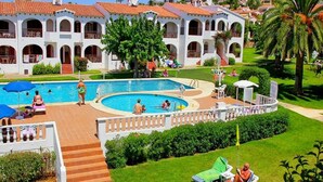 Et resort med swimmingpool, liggestole og en hvid bygning med hvælvinger.