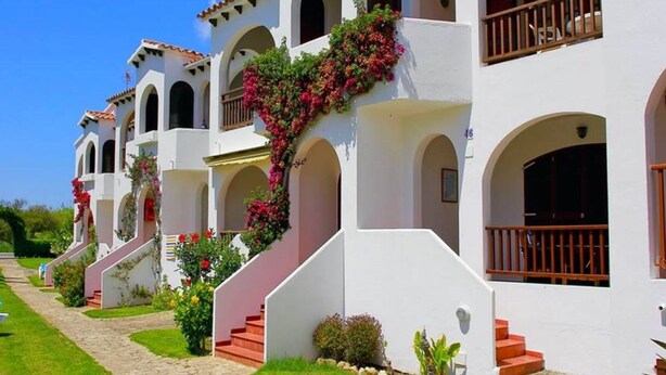 A row of white buildings with arched windows and balconies, numbered 45 to 49, with a clear sky in the background. - Apartment in Well-Maintained Complex with Pool - Girasol Garden Superior 2 F (menorca)