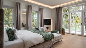 A bedroom with a large bed, a TV, and a view of the outdoors. - Schlossresidenz Boutique Apartements & Hotel Suiten (Garbsen)