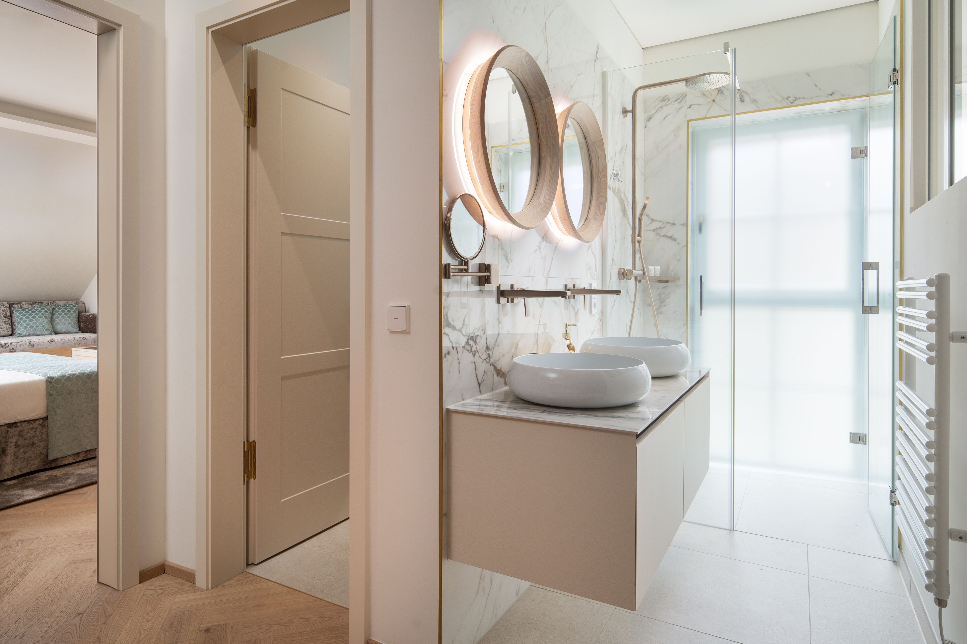 A modern bathroom with a marble backsplash, two round mirrors, and a large sink.