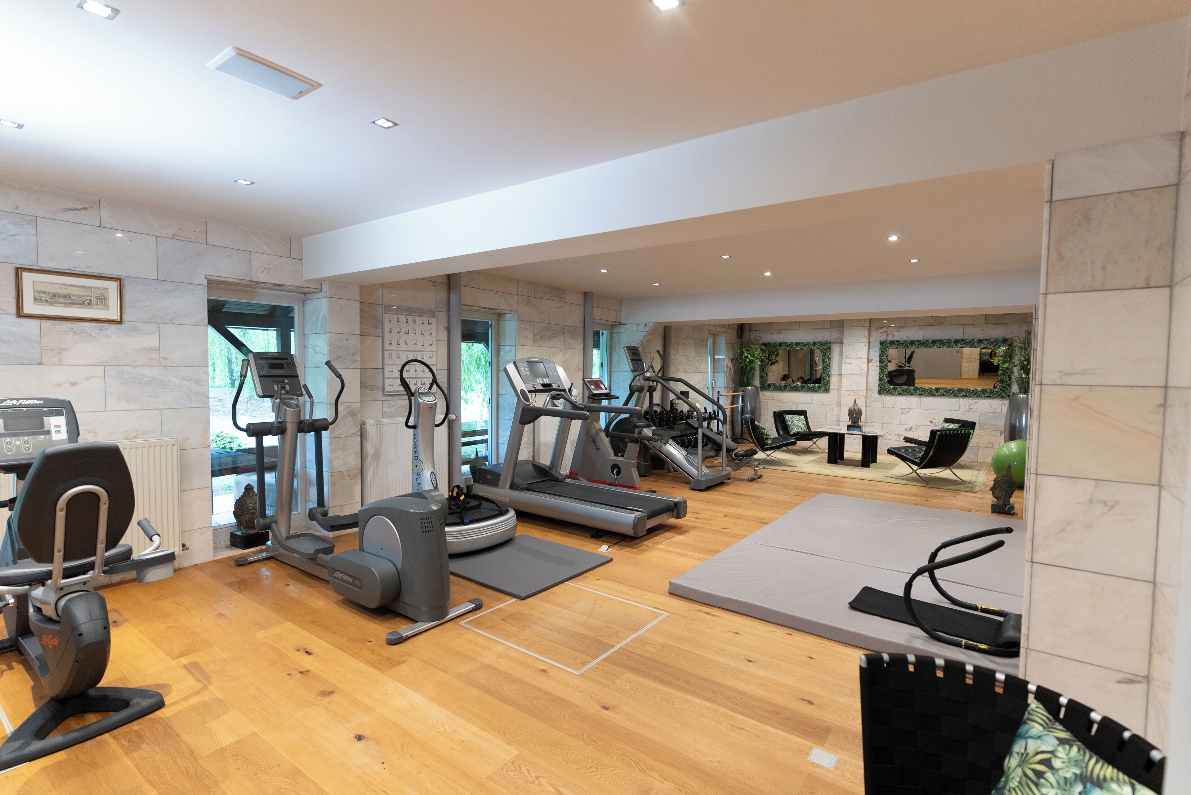 Une salle de sport spacieuse équipée de divers appareils d’exercice, notamment des tapis de course et des vélos elliptiques, et dotée d’un plancher en bois.