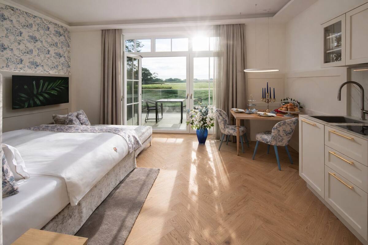 Une chambre à coucher comprenant un lit, un bureau et donnant sur un jardin grâce à une porte coulissante.