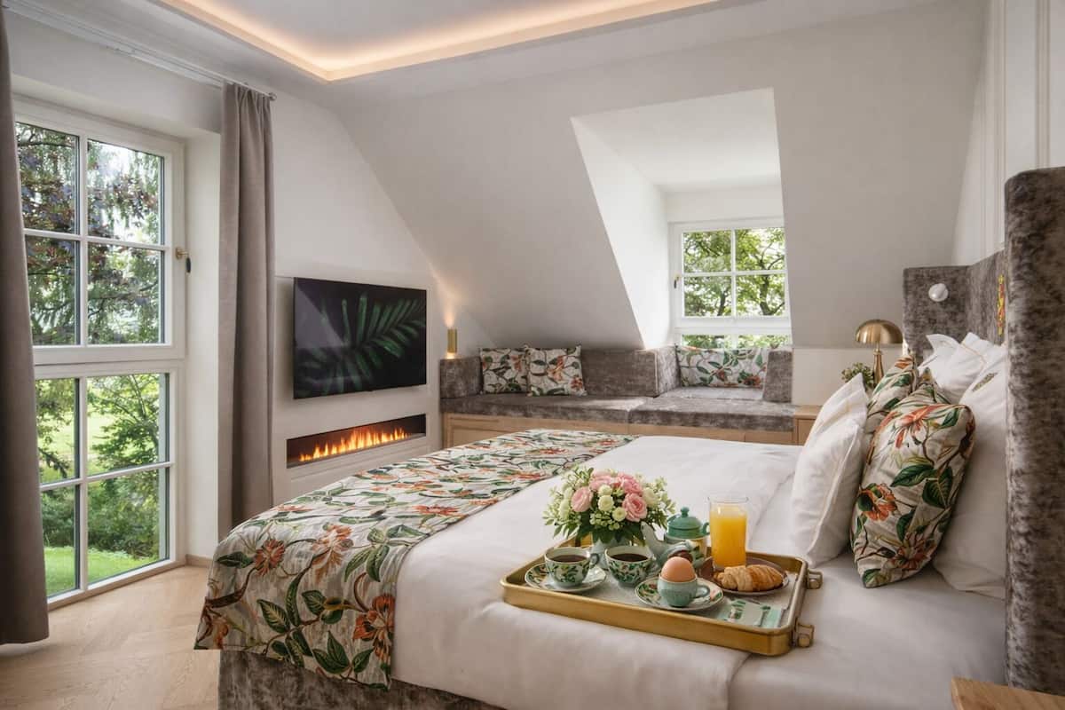 Une chambre avec un grand lit, une cheminée, une télévision et un balcon.