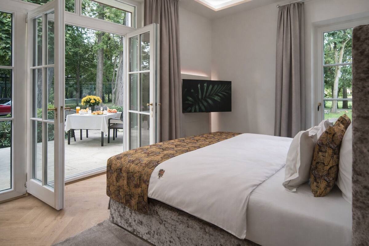 Une chambre dotée d’un grand lit, d’un téléviseur fixé au mur et d’une porte-fenêtre coulissante donnant sur un espace repas extérieur.