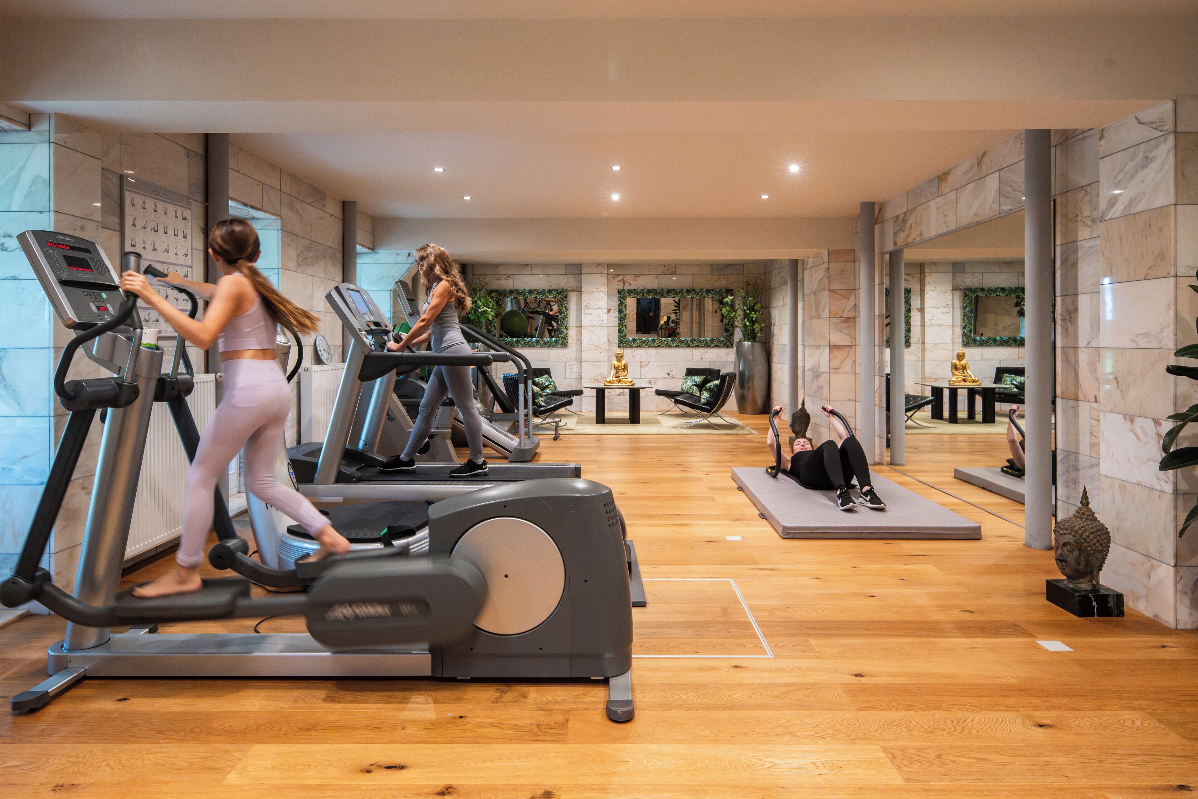 Een sportschool met loopbanden, een yogaruimte en een standbeeld.