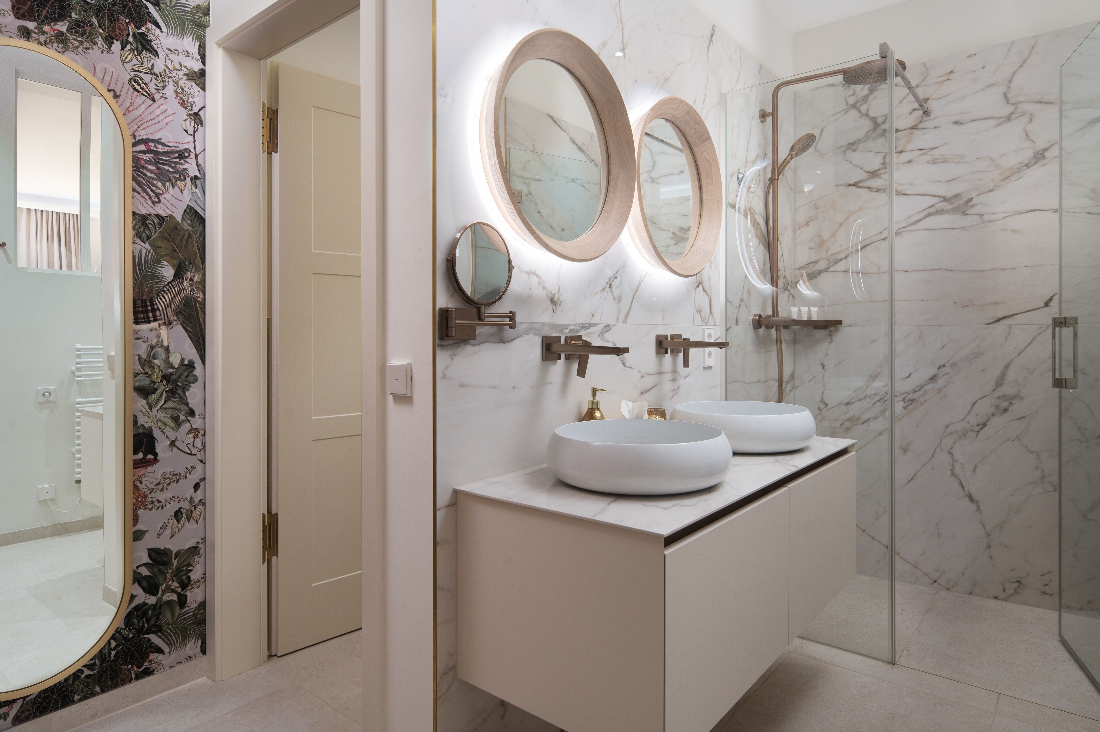 A modern bathroom with two sinks, a shower, and a large mirror.