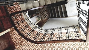 Un escalier en colimaçon avec un sol à motifs et des rampes en métal.