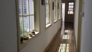 Un couloir doté d’un sol carrelé à motifs, de nombreuses fenêtres et offrant une vue sur l’extérieur.
