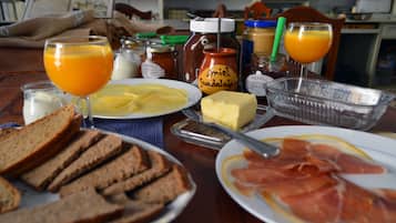 A breakfast table with bread, butter, ham, and orange juice.