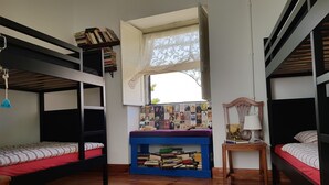 Une chambre de dortoir avec des lits superposés, un bureau avec des livres, une fenêtre et une lampe.