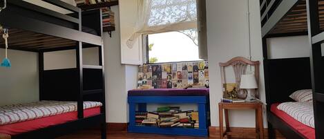 Un dormitorio con literas, un escritorio con libros, una ventana y una lámpara.