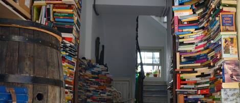 Un couloir étroit, bordé de bibliothèques de part et d’autre, avec un tonneau en bois et un sol à motifs.