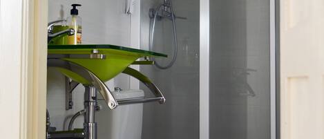 Une salle de bain avec des toilettes, un lavabo vert et une douche.
