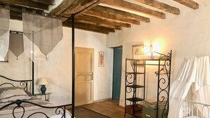 Une chambre à coucher comprenant un lit, une table de chevet, une lampe, une armoire et un panier suspendu.