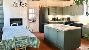 Une cuisine avec un îlot central, une table à manger avec des chaises et une cheminée.