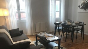 A living room with a sofa, coffee table, dining table with chairs, and a patterned rug. - CENTER - SPACIOUS - COZY - WIFI (Albi)
