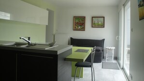 A modern kitchen with a sink and a dining area. There are two paintings on the wall. - Bright house with garden and terraces. (Concarneau)