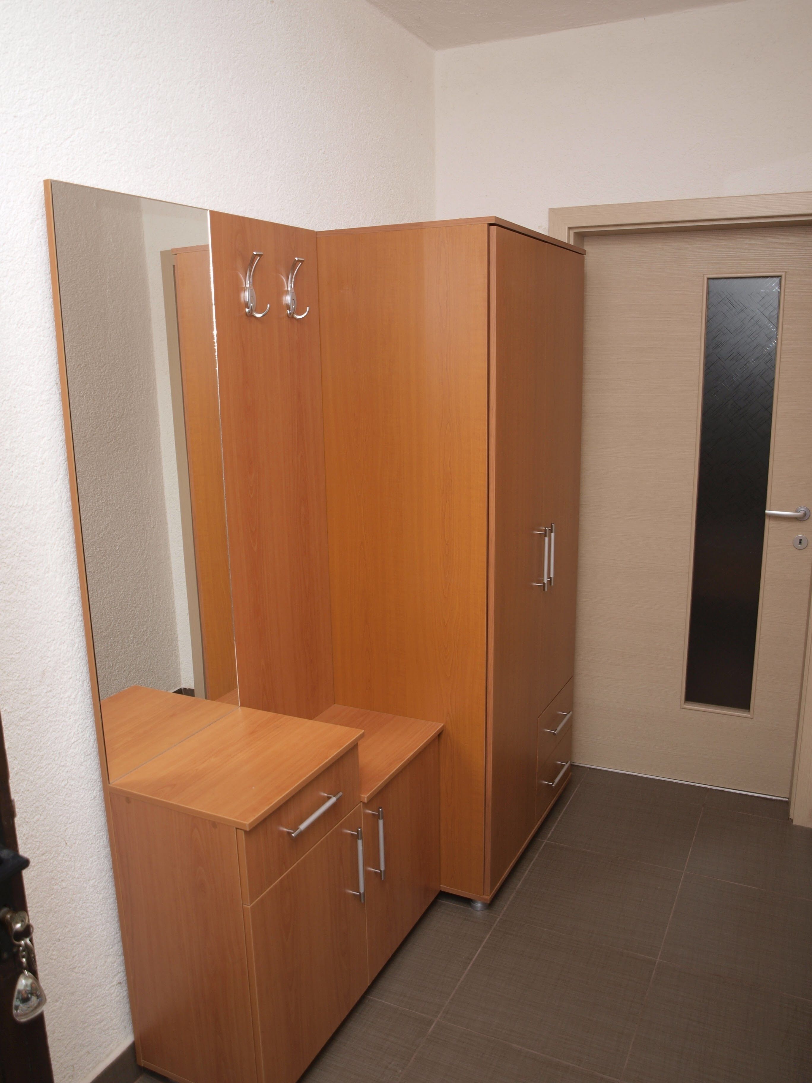 A room with a wooden wardrobe, a mirror, and a door with a frosted glass panel.