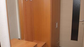 A room with a wooden wardrobe, a mirror, and a door with a frosted glass panel.