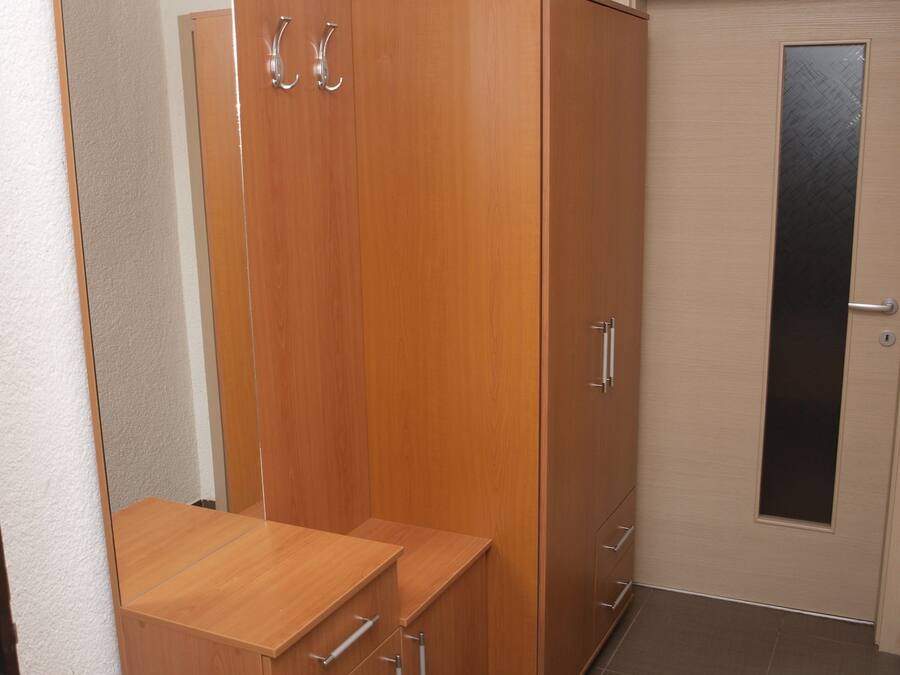 A room with a wooden wardrobe, a mirror, and a door with a frosted glass panel.