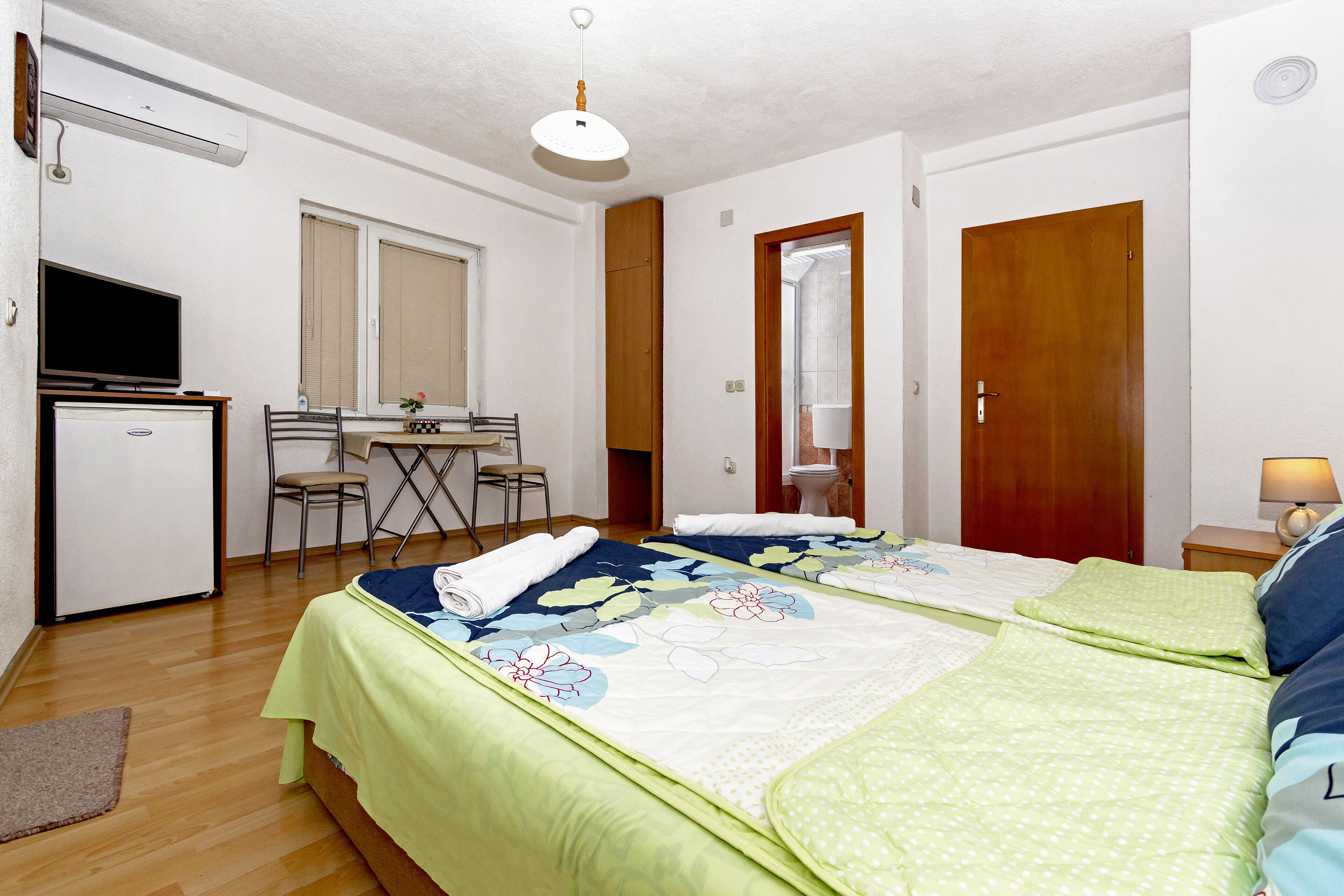 Una habitación con dos camas, un escritorio, una silla y una televisión.
