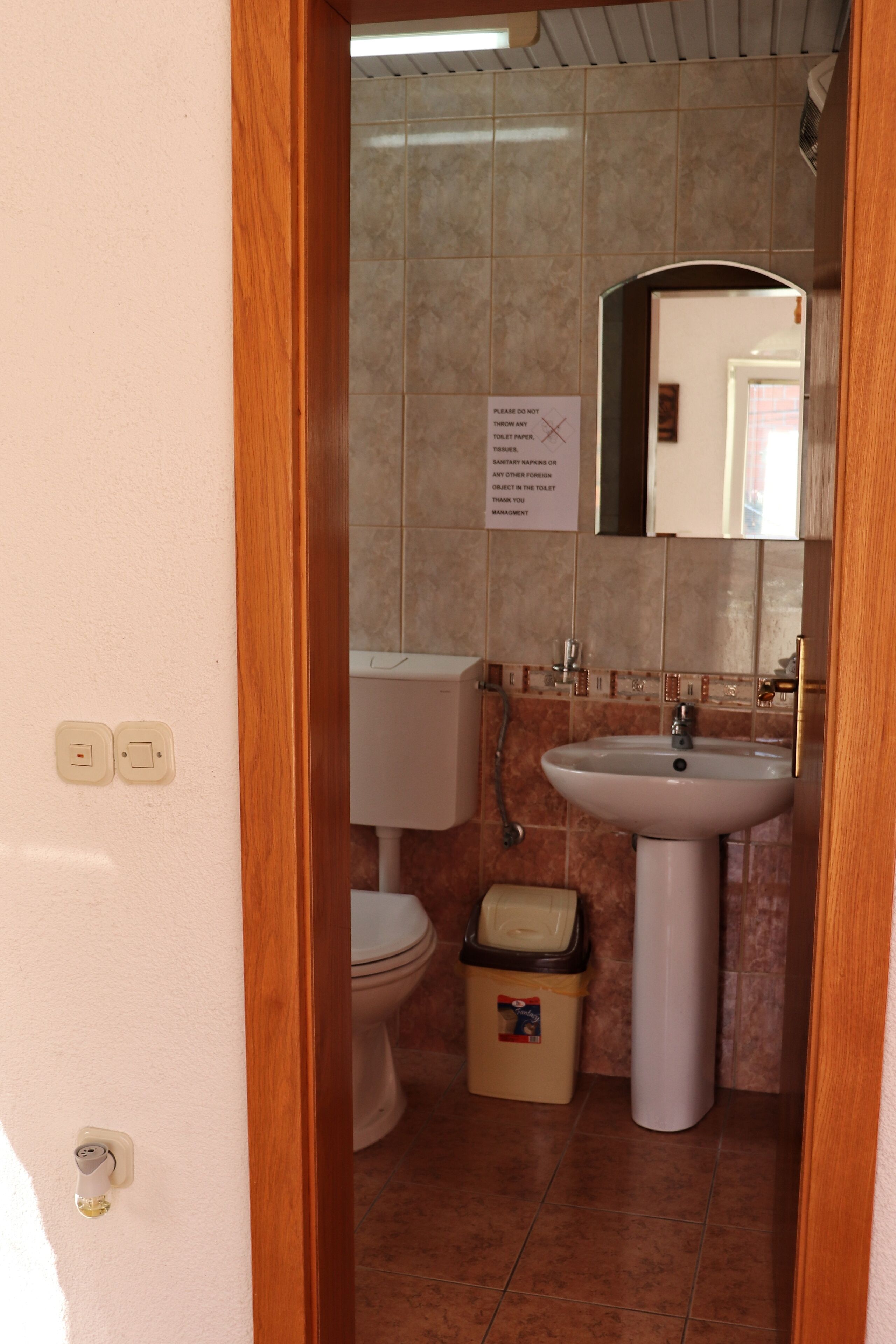 Een badkamer met toilet, wastafel en prullenbak.